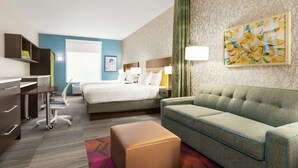 Een hotelkamer met een bed, een slaapbank, een bureau en een stoel.