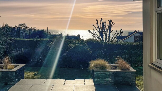 Un patio con vista al mar, macetas de piedra y cielo despejado.