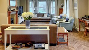 Una sala de estar con sofá, sillones, una mesa de centro y televisión.