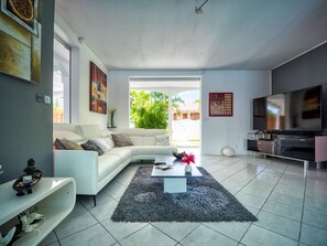 A modern living room with a white sofa, a coffee table, and a flat-screen TV.