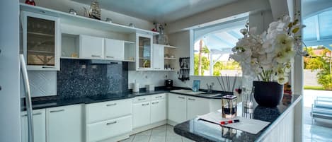 A modern kitchen with white cabinetry, a black countertop, and a window with a view of greenery.