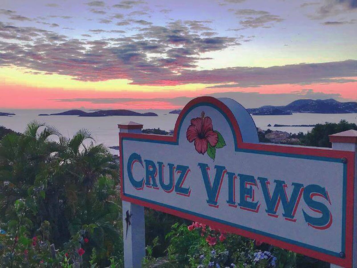 Schild mit der Aufschrift 'Cruz Views' und einem floralen Emblem, umgeben von viel Grün.