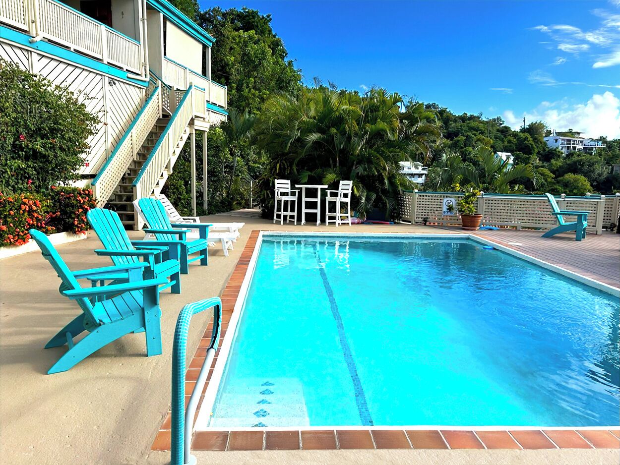 A swimming pool with blue chairs and a staircase leading to a building.