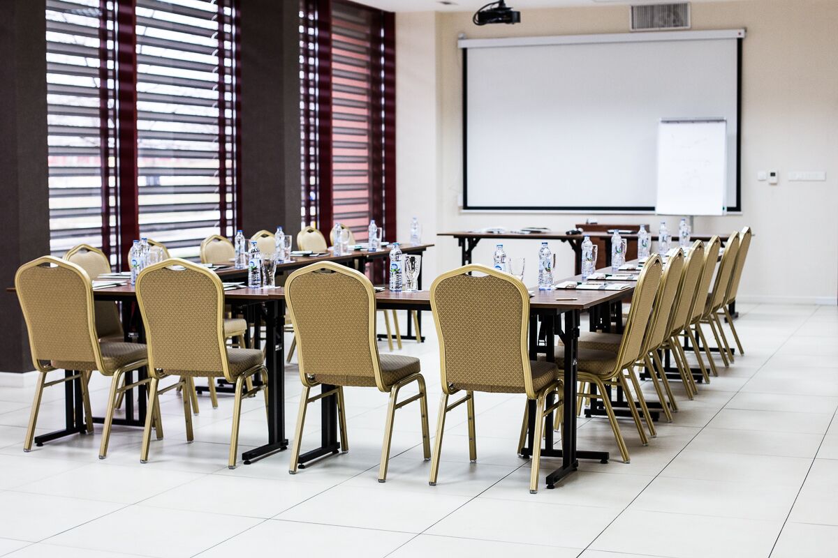 A conference room with a long table, chairs, a projector screen, and a whiteboard.