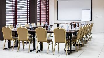 A conference room with a long table, chairs, a projector screen, and a whiteboard.
