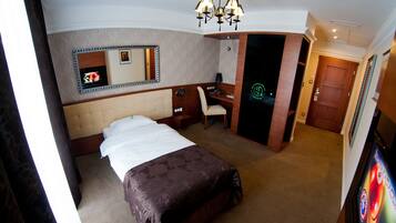 Una habitación de hotel con cama, escritorio, silla, espejo y puerta.