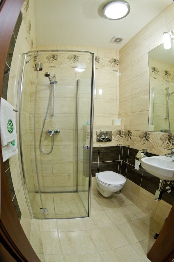 Un baño con ducha de vidrio, inodoro y lavamanos.