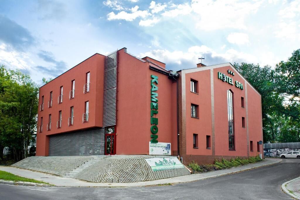 A red building with a sign reading "HOTEL SPA" and "KAMENITON".