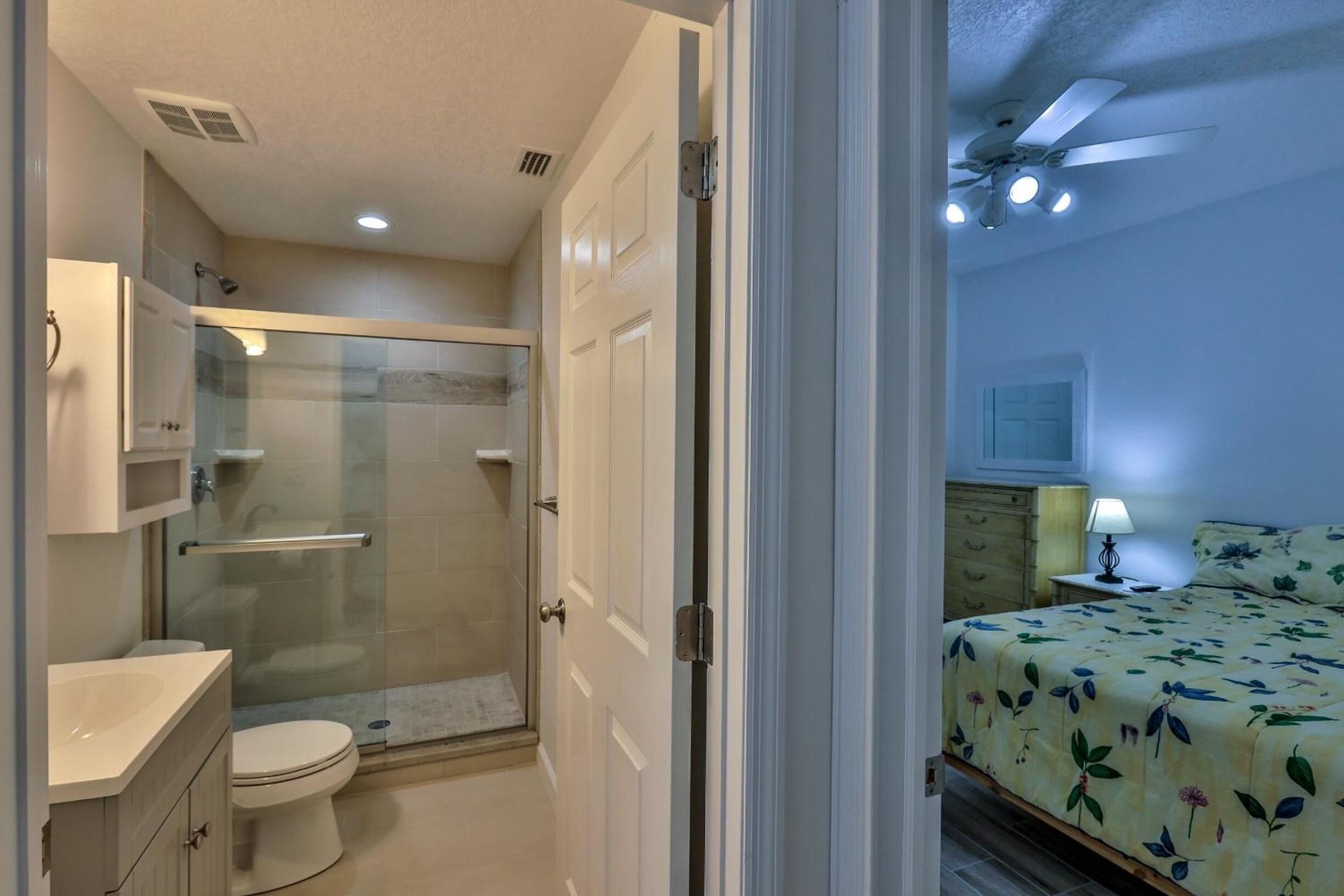 A bathroom with a glass shower enclosure, a toilet, and a vanity with a sink.