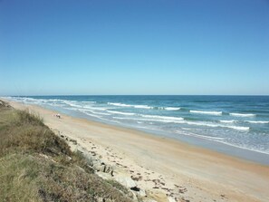 A beach with waves, a clear sky, and a sandy path. - Flagler Beach Motel and Vacation Rentals (Flagler Beach)