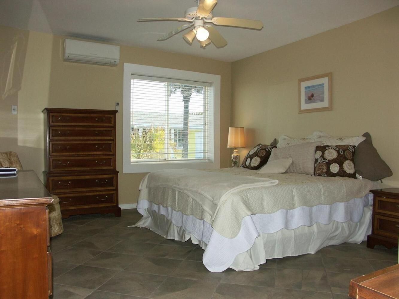 A bedroom with a bed, dresser, nightstand, and a ceiling fan.