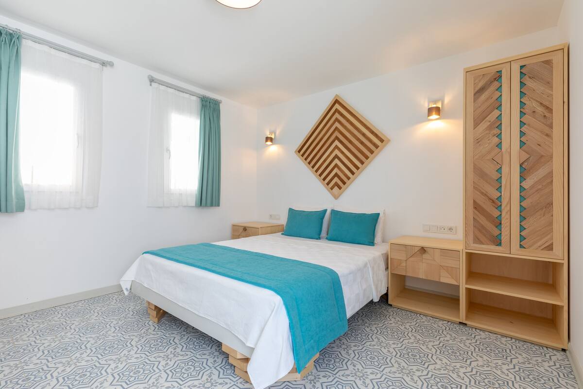 Ein Schlafzimmer mit einem Bett, einem Nachttisch, einem Kleiderschrank und einer Wandleuchte.