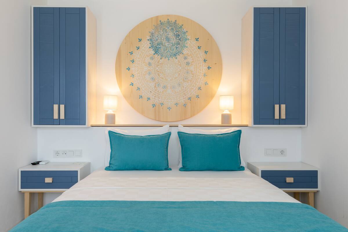 Ein Schlafzimmer mit einem Bett, zwei Nachttischen, einem an der Wand befestigten runden Kunstwerk und zwei Schränken.
