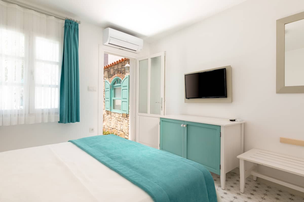 Ein Schlafzimmer mit einem Bett, einem Fernseher, einem Kleiderschrank und einem Fenster mit Vorhängen.