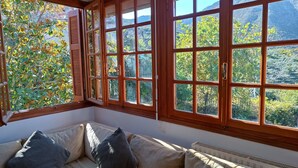 Una habitación con un ventanal grande, un sofá color crema con cojines y un radiador.
