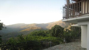 Un balcón empedrado con barandilla de metal que da a un paisaje montañoso.