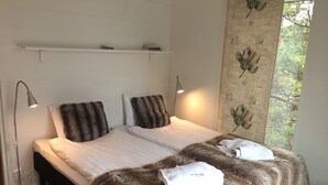 A double bed with a fur throw, a bedside lamp, and a towel on the bed. - Seaside villa in the Nordic Archipelago (Geta)