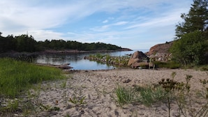 A natural landscape with a sandy beach, a calm river, and a forested area in the background. - Seaside villa in the Nordic Archipelago (Geta)