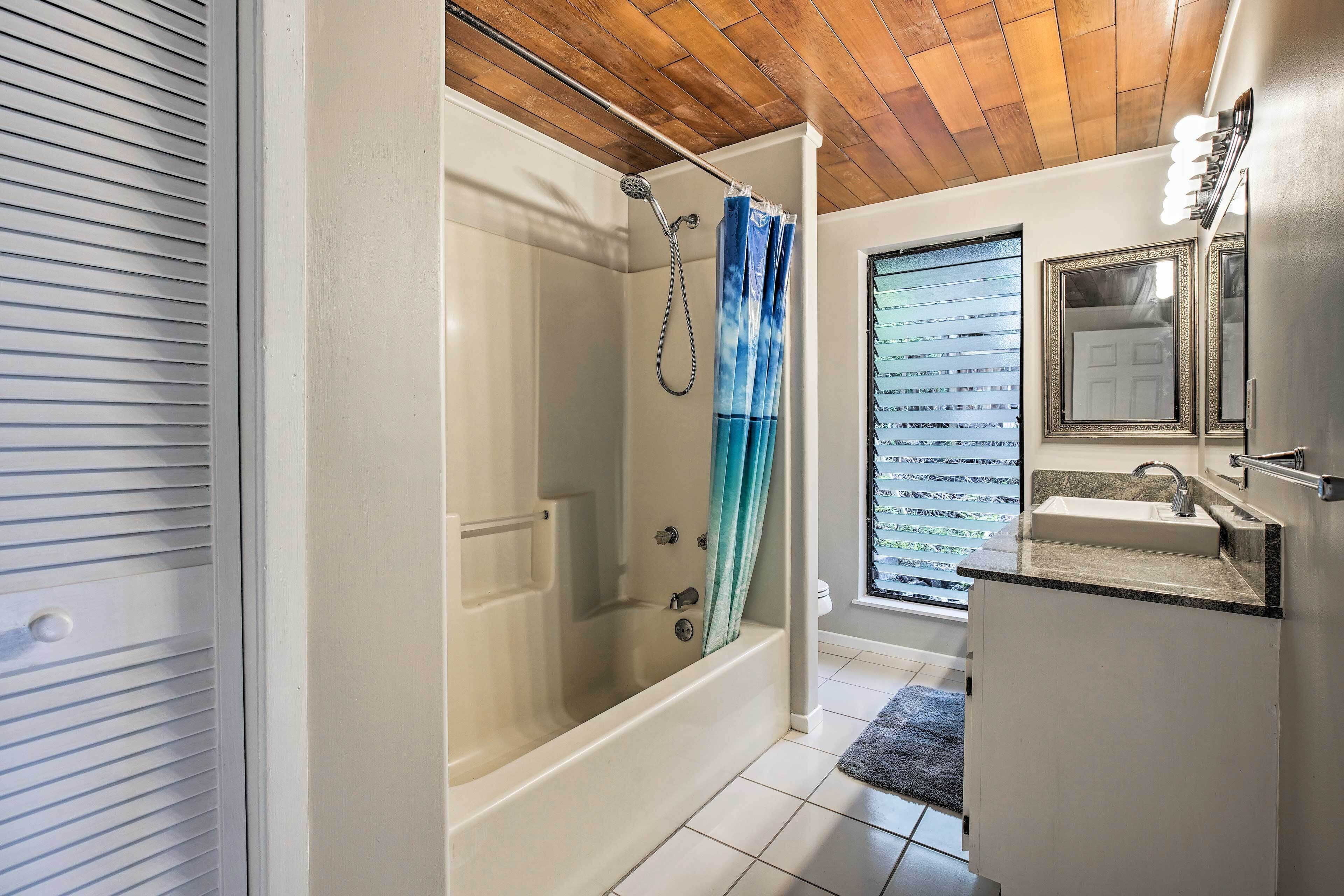 Une salle de bain moderne avec une douche à l’italienne, un meuble-lavabo et une fenêtre équipée de stores.