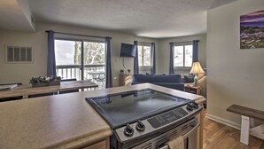A compact kitchen with a gas stove, a dining table, and a TV mounted on the wall. - Ski-In Ski-Out Wintergreen Condo w/ Balcony (Wintergreen Resort)