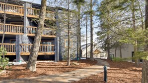 A multi-story building with balconies, surrounded by trees and a clear sky. - Ski-In Ski-Out Wintergreen Condo w/ Balcony (Wintergreen Resort)