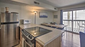 A modern kitchen with stainless steel appliances, a built-in stove, and a dining area with a view of the balcony. - Ski-In Ski-Out Wintergreen Condo w/ Balcony (Wintergreen Resort)