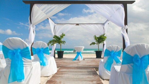 A wooden pier leading to a beach wedding setup with white chairs and blue sashes, under a white canopy. - Wahoo Chateau with Low-Speed Vehicle, Heated Pool, and Cornhole Field (Miramar Beach)