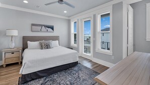 A bedroom with a large bed, a ceiling fan, and a view of the outside through the windows. - Wahoo Chateau with Low-Speed Vehicle, Heated Pool, and Cornhole Field (Miramar Beach)