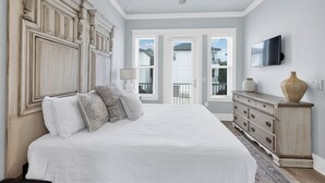 A bedroom with a large bed, a ceiling fan, a dresser, and a TV on the wall. - Wahoo Chateau with Low-Speed Vehicle, Heated Pool, and Cornhole Field (Miramar Beach)