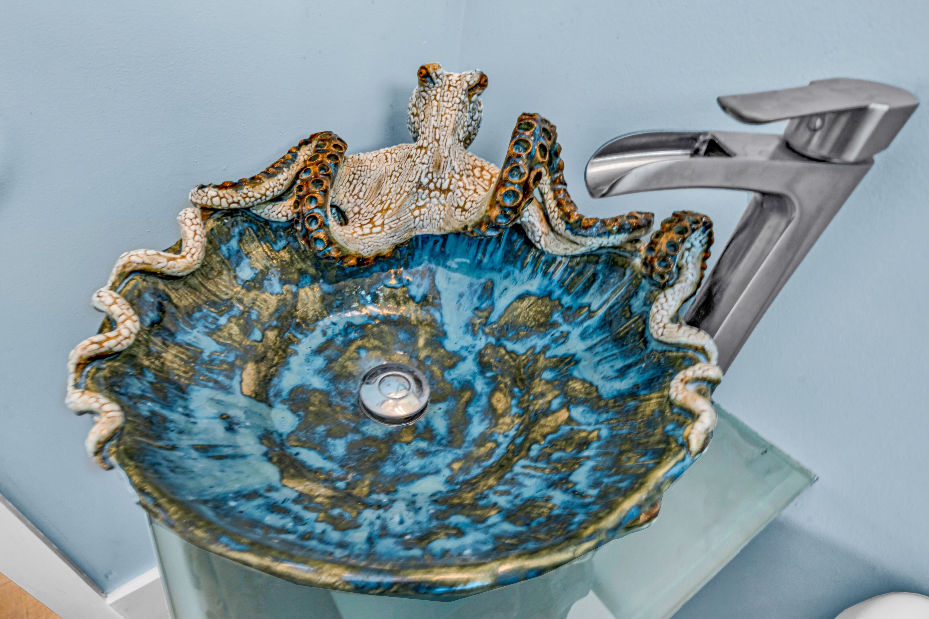 Un lavamanos azul de cerámica con diseño de pulpo.