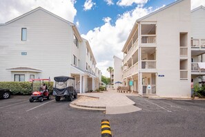A residential street with two-story buildings, a parking area, and a covered parking space.