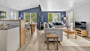 A modern living room with a fireplace, sofa, TV, and dining area. - The Retreat, Strawberryfield Park -  a lodge that sleeps 4 guests  in 2 bedrooms (Cheddar)