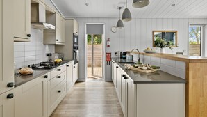 A modern kitchen with a central island, built-in appliances, and pendant lighting. - The Retreat, Strawberryfield Park -  a lodge that sleeps 4 guests  in 2 bedrooms (Cheddar)