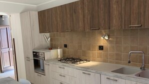 A modern kitchen with wooden cabinets, a gas stove, a sink, and a ceiling fan. - An oasis of peace among secular olive trees (San Pietro Infine)