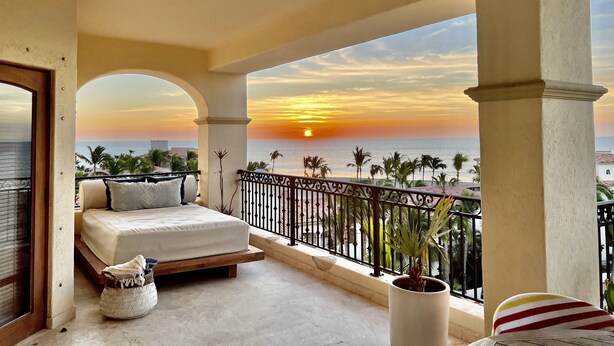 A balcony with a bed, a potted plant, and a view of the sunset over the ocean. - Triple En-suite on the beach at Las Mananitas  (San Jose del cabo)