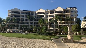A beachfront hotel with multiple balconies, palm trees, and a sandy walkway. - Triple En-suite on the beach at Las Mananitas  (San Jose del cabo)