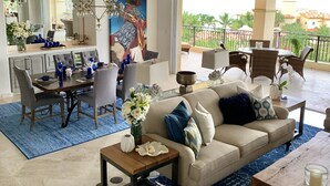 A spacious living room with a beige sofa, a dining area with a large mirror, and a balcony with outdoor furniture. - Triple En-suite on the beach at Las Mananitas  (San Jose del cabo)