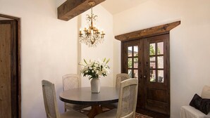 Ein Essbereich mit einem runden Tisch, vier Stühlen, einer Chandelierleuchtre, einer Blumenvase und einer Holztür.