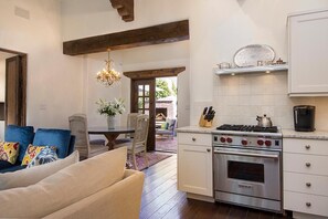 A kitchen with a built-in oven, a dining area with a table and chairs, and a chandelier.