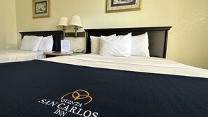 A hotel room with two beds, a nightstand, a lamp, and framed artwork on the wall.