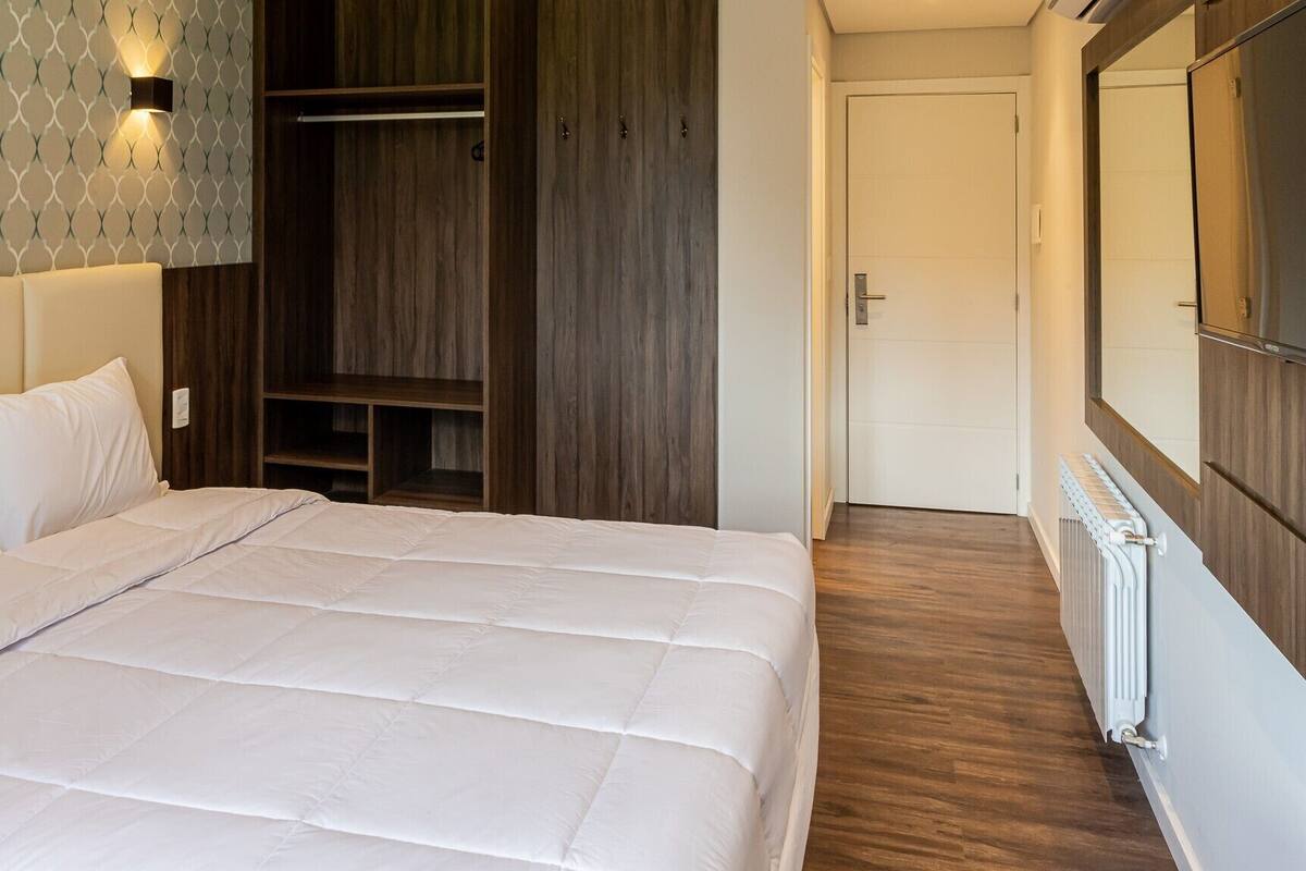 Un dormitorio con una cama grande, armario de madera y vestidor.