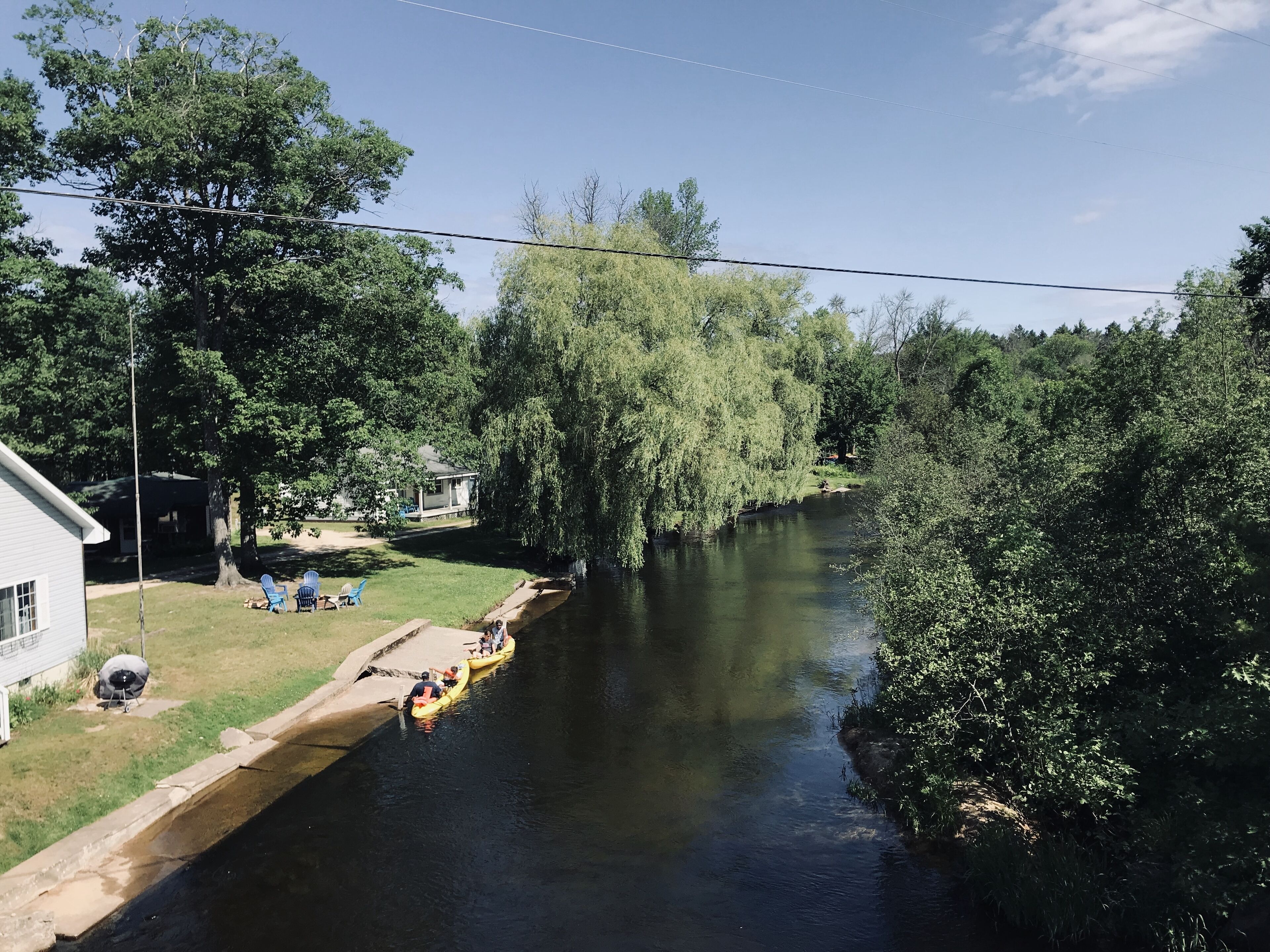 Een rivier met een smalle betonnen looppad, omringd door weelderige begroeiing en bomen.