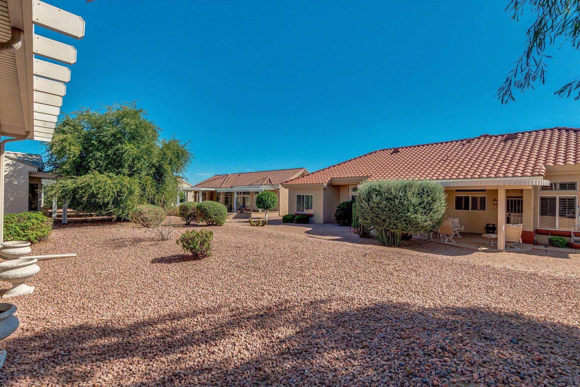 A residential area with multiple houses, a gravel driveway, and well-maintained landscaping.