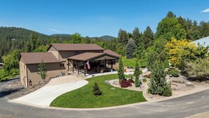 A two-story house with a covered patio and a driveway. - Large 7BR Home Near Lake CDA | Backyard Oasis & Game Room (Coeur d'Alene)