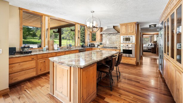A spacious kitchen with wooden cabinets, a large island, and a view of a green landscape. - Large 7BR Home Near Lake CDA | Backyard Oasis & Game Room (Coeur d'Alene)