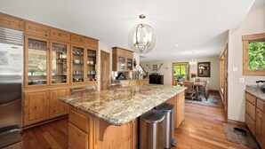A spacious kitchen with wooden cabinets, granite countertops, stainless steel appliances, and a central island. - Large 7BR Home Near Lake CDA | Backyard Oasis & Game Room (Coeur d'Alene)