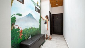 A person painting a mural on a wall in a hallway. - La Fortuna Lodge by Treebu Hotels (La Fortuna)