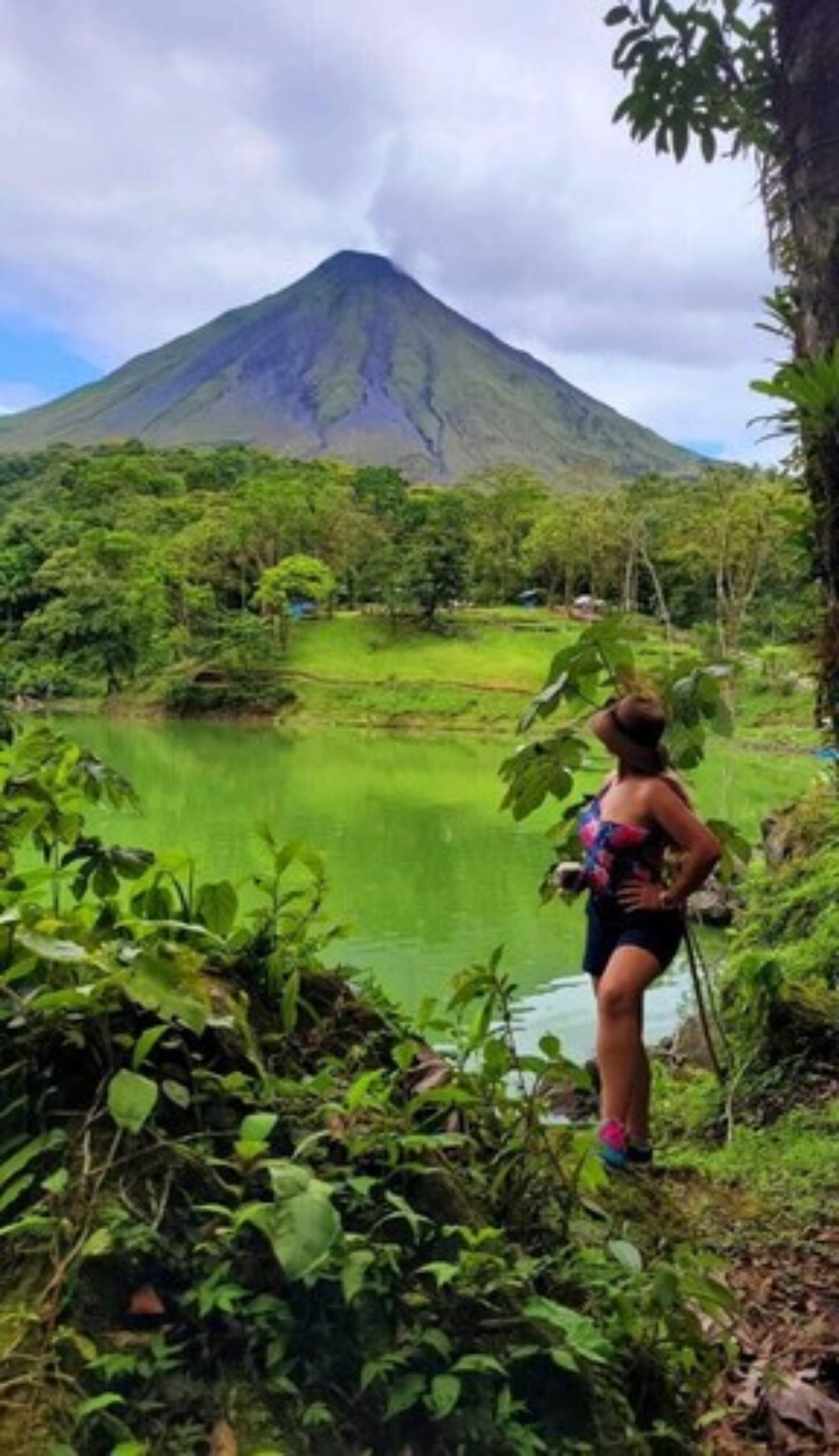 A person standing by a lake with a mountain in the background.