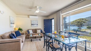Ein modernes Wohnzimmer mit einem Glastisch, einer Couch und einem Deckenventilator.