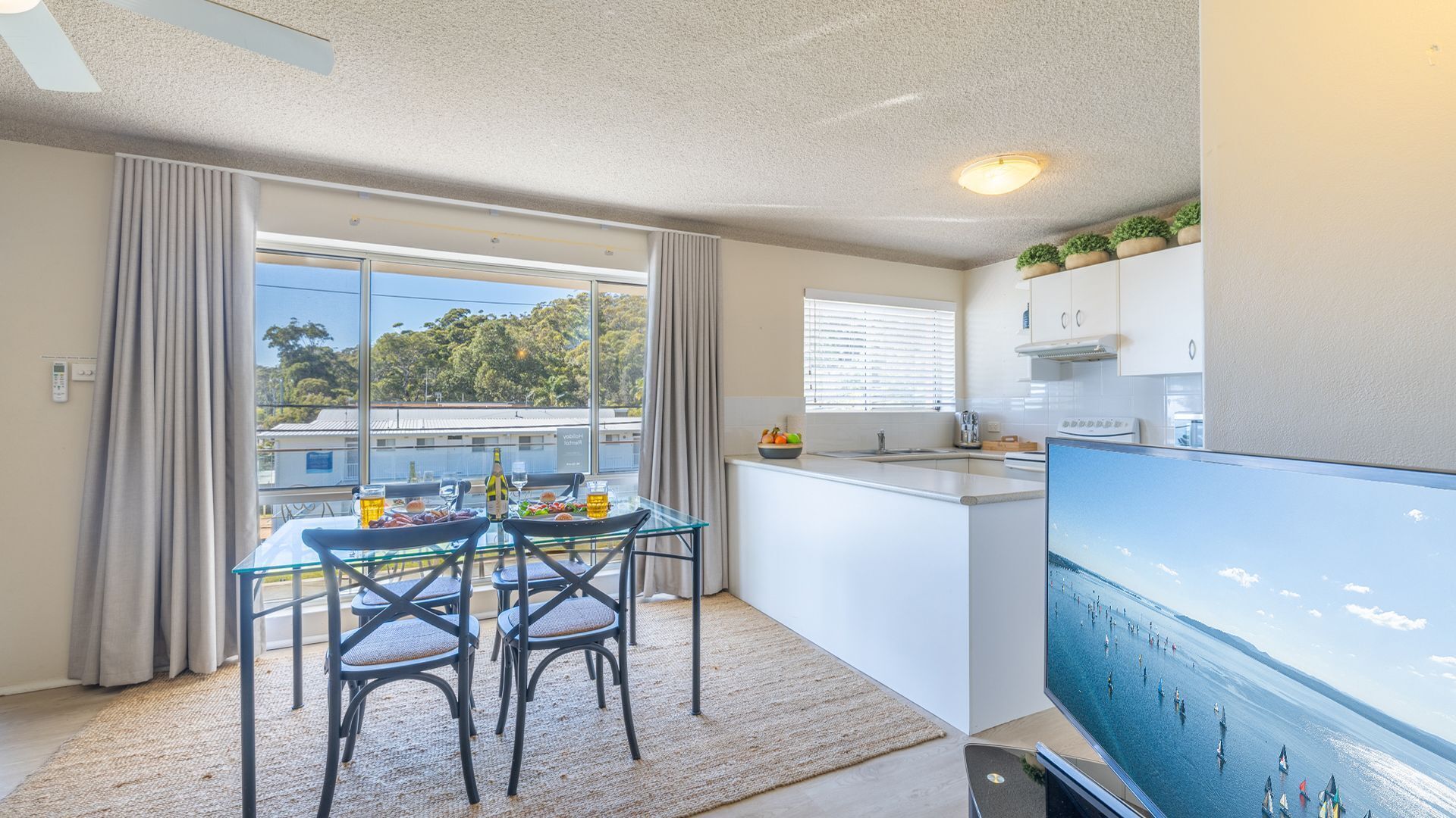 Una cocina moderna con comedor, ventanas amplias y un televisor de pantalla plana.